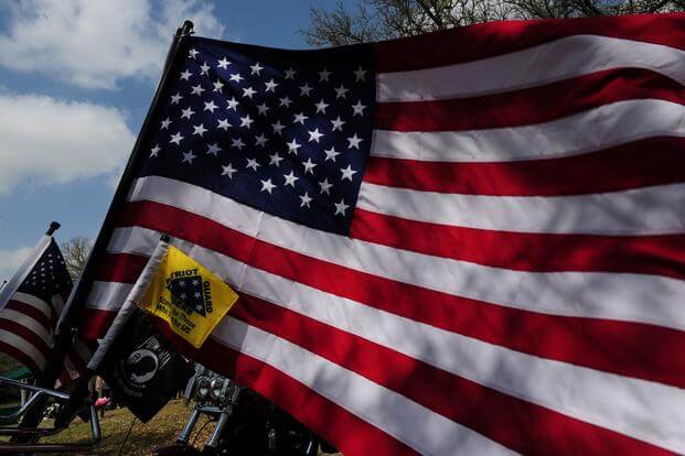 an American flag and other flags are displayed at a veteran's funeral